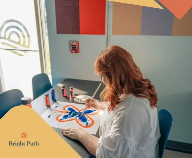 Teen painting a butterfly during a creative therapy activity at Bright Path