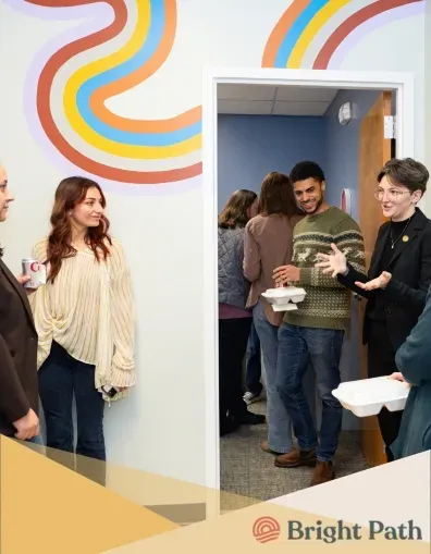 Guests talking in a Bright Path hallway with a rainbow mural