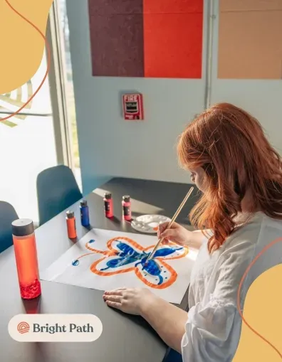 Teen painting a butterfly during a creative therapy activity at Bright Path
