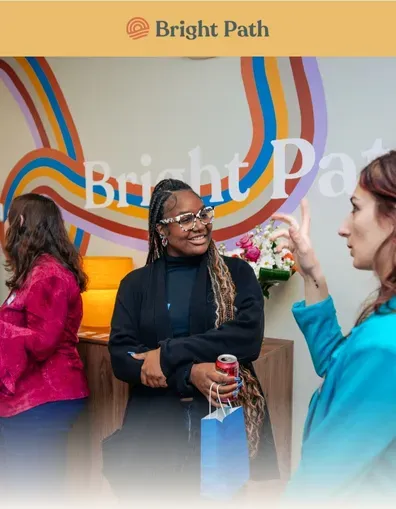 Guests talking beside the Bright Path rainbow mural at an open house