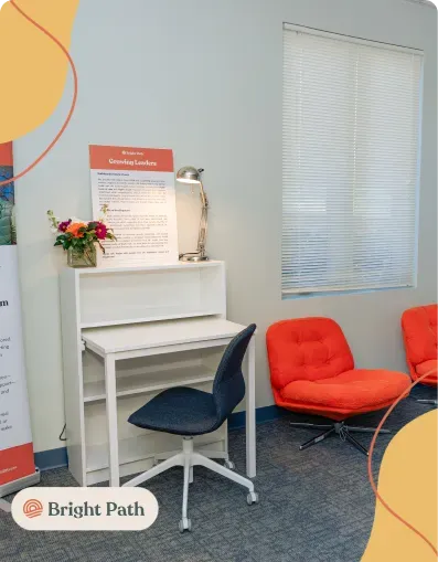 Study nook with a white desk and orange lounge chairs at Bright Path