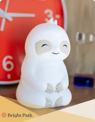 White sloth figure beside a red wall clock at Bright Path