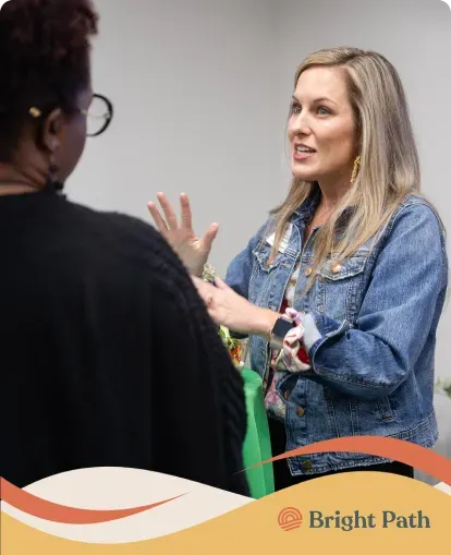 Woman in a denim jacket talking with a guest at Bright Path