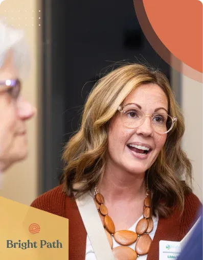 Smiling woman with glasses talking with guests at a Bright Path event