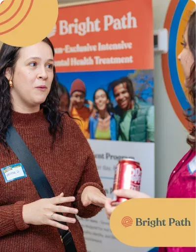 Woman with a name tag talking in front of a Bright Path program banner