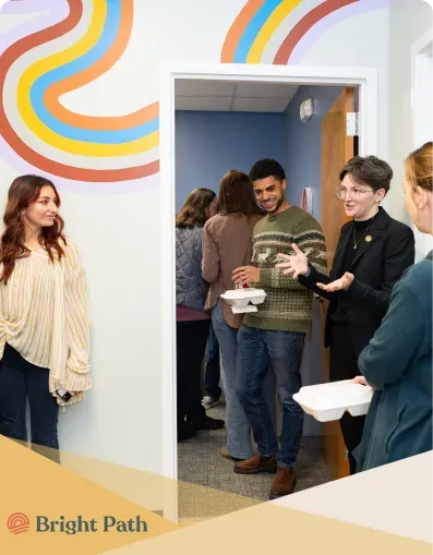 Visitors gathered in a doorway beneath the rainbow mural at Bright Path