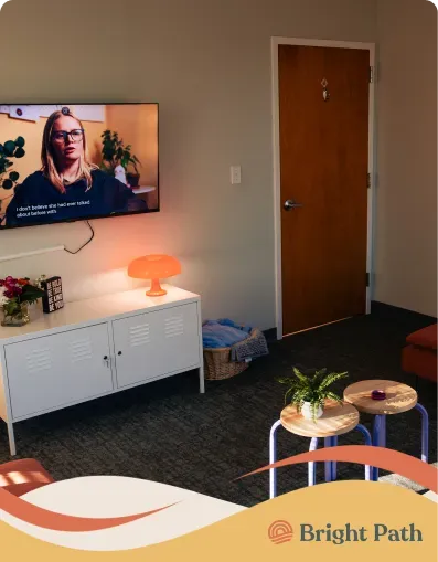 Teen lounge at Bright Path with a TV, a mushroom lamp and wooden stools