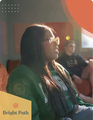 Teen in a green sweatshirt listening during a group session at Bright Path