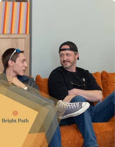Two men talking on an orange couch at Bright Path