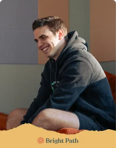 Young man smiling on an orange couch at Bright Path