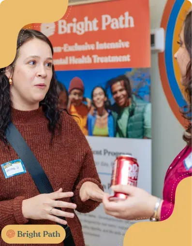 Woman with a name tag talking in front of a Bright Path program banner