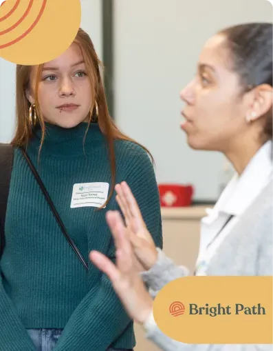 Young woman with a name tag in an open conversation with a woman at Bright Path