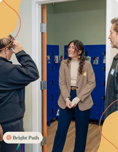 Woman in a tweed blazer standing in a doorway in front of blue lockers at Bright Path