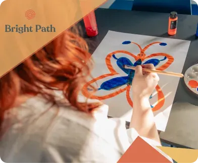 A person painting an orange and blue butterfly at Bright Path