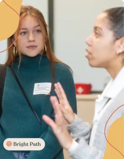 Young woman wearing a name tag talking with a guest at a Bright Path event