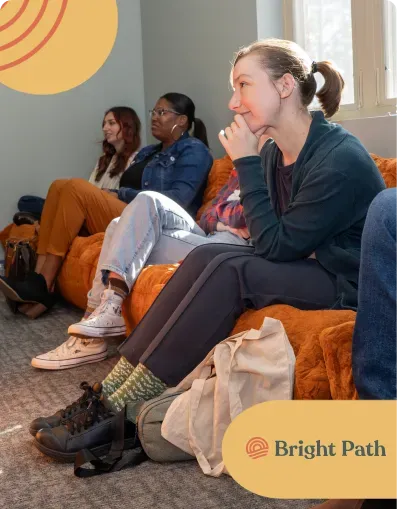 Young people seated on orange lounge chairs listening during a Bright Path gathering