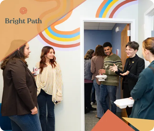 Guests chatting in a Bright Path hallway beside a rainbow mural and an open doorway