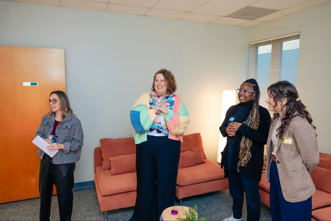 Four women chatting in a pale blue Bright Path room with a coral sofa