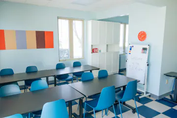 Bright Path art room with rows of blue chairs, dark tables and a welcome whiteboard
