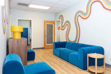 Common area with blue sofas and a rainbow mural at Bright Path