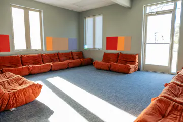 Sunlit Bright Path group room ringed with orange floor couches