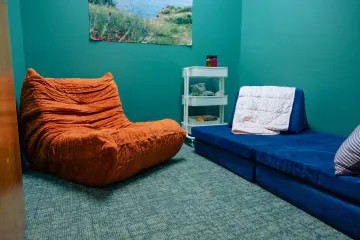 Small therapy room with a soft lounge chair and a blue sofa at Bright Path