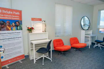 Bright Path waiting area with two orange swivel chairs, a writing desk and a program banner