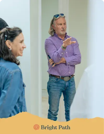 Man in a purple checked shirt talking with visitors inside Bright Path
