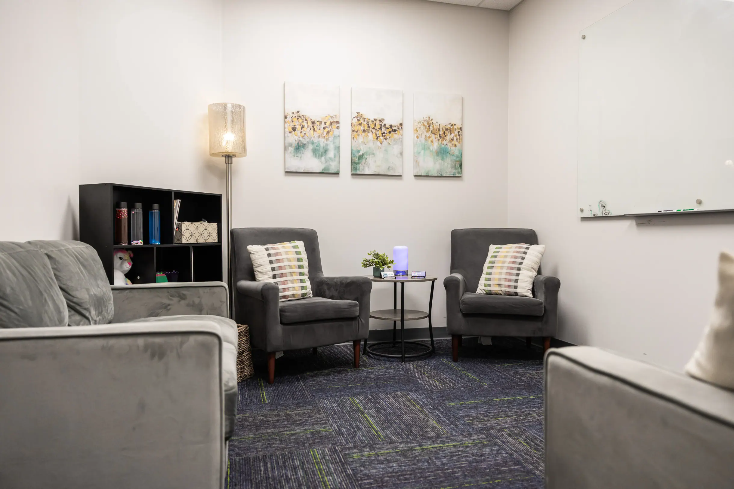 Family therapy and admissions room with gray sofas and armchairs at Bright Path Wake Forest