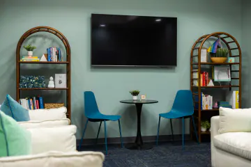 Teen lounge at Bright Path Wake Forest with teal walls, bookshelves and a TV